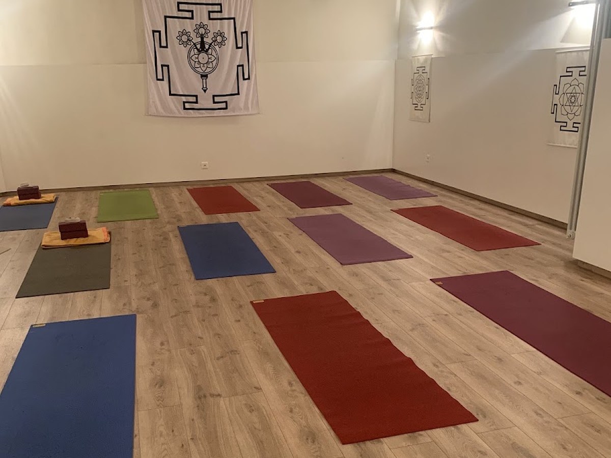 Salle de yoga du Centre Shambala à Carouge : tapis colorés au sol et tentures yantra aux murs
